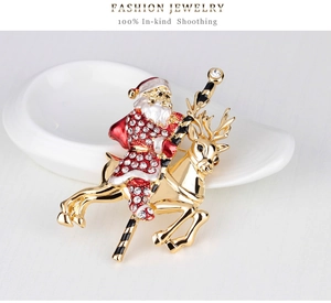 Detailed view of gold Christmas brooch with Santa Claus on reindeer and white rhinestones
