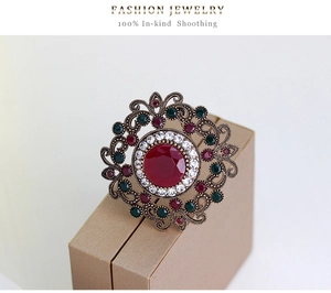 Close-up of vintage hollowed brooch with red gemstone and green stones on a jewelry box