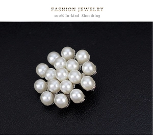 Détail de la broche fleurie tendance avec perles rondes et strass étincelants