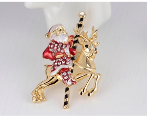 Close-up of Santa Claus riding a gold reindeer brooch with enamel and crystals