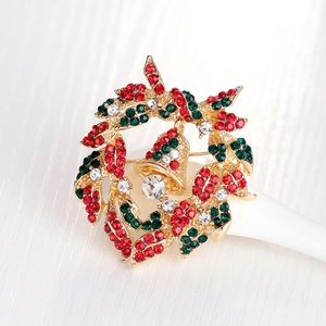 Christmas wreath brooch with colorful rhinestones and golden bell on white display