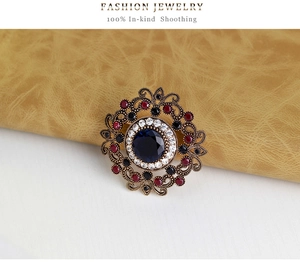 Detailed macro shot of vintage hollow brooch with blue gemstone and colorful crystals
