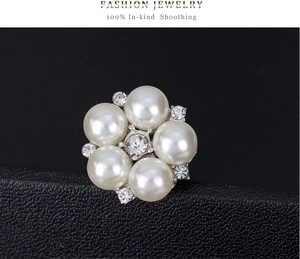 Detailed close-up of a flower brooch with white pearls and sparkling central crystals