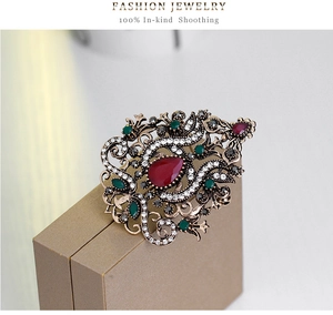Detailed view of a vintage crown brooch with red teardrop stones and white crystals