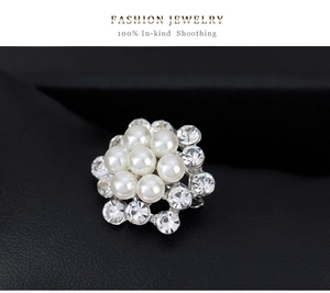Dettaglio di elegante spilla floreale con grappoli di perle bianche e strass scintillanti