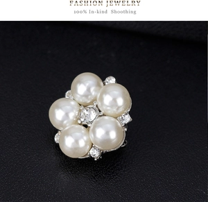 Macro detail of silver floral brooch featuring white pearls and clear crystal accents
