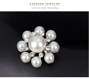 Vue macro d'une broche perle en forme de fleur avec strass sur fond de cuir noir