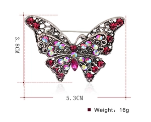 Dettaglio spilla a farfalla vintage con strass rossi e dimensioni di 5,3cm di larghezza