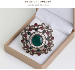 Macro shot of vintage style hollow carved brooch with green oval gemstone and diamonds