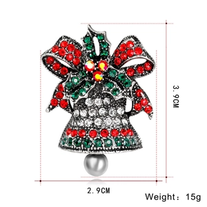 Detail view of a Christmas bell brooch with red and green rhinestones and a grey pearl bead