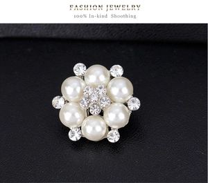 Macro di una spilla a fiore in argento con perle finte bianche e strass chiari