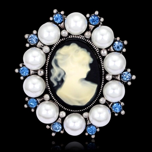 Vintage cameo brooch with black profile and blue rhinestones on black reflection