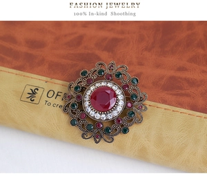 Detail view of a vintage baroque brooch with a large red gemstone on a brown notebook