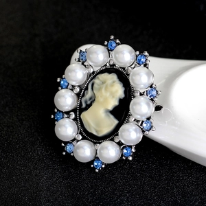 Vintage oval cameo brooch with pearls and blue rhinestones on a black background