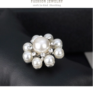 Gros plan d'une broche fleur avec perle centrale et cristaux sur du cuir noir texturé