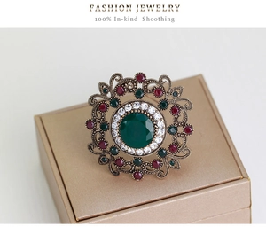 Macro detail of luxury vintage brooch featuring hollow-out diamond and green gemstone