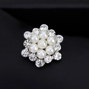 Elegante spilla a fiore d'argento con perle bianche e cristalli su sfondo scuro