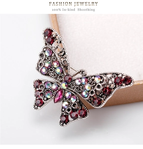 Macro detail of vintage hollow-out butterfly brooch with deep red and iridescent rhinestones