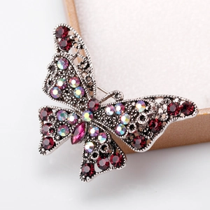 Vintage silver butterfly brooch featuring red rhinestones and iridescent crystals