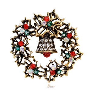 Macro shot of retro gold Christmas wreath brooch with bells and multicolored rhinestones
