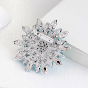 Silver sunflower brooch back view with blue crystal accents and secure pin closure