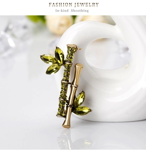 Détail d'une broche bambou avec cristaux vert olive et métal doré brillant