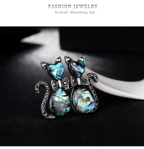 Detail of couple cats brooch featuring iridescent abalone shell and black rhinestones