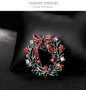 Detailed close-up of a Christmas wreath brooch with sparkling red, green, and white rhinestones