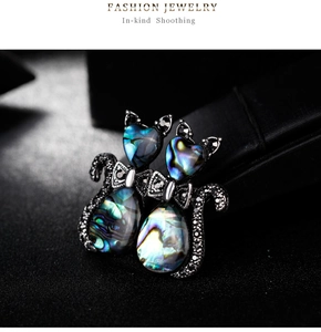 Detailed close-up of retro cat brooches with abalone shell inlays and black rhinestones