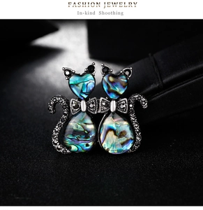 Macro detail of cat brooches with colorful abalone shell inlay and black crystals