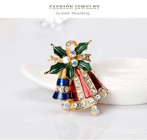 Détail d'une broche de cloche de Noël avec émail coloré et strass scintillants