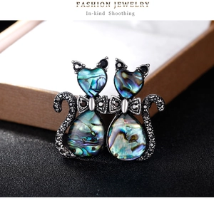 Detailed macro view of cat brooches with colorful abalone shell and black rhinestones