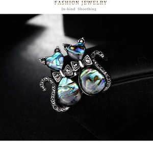 Macro shot of vintage twin cats brooch with iridescent shell and sparkling rhinestones