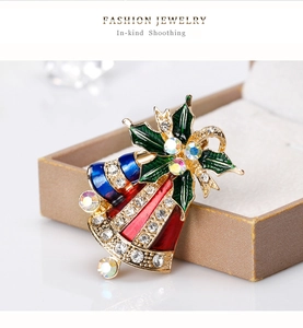 Détail macro d'une broche cloche de Noël en émail coloré avec strass scintillants