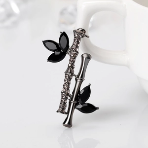 Broche en bambou en alliage avec strass noirs et cristaux sur fond de céramique blanche