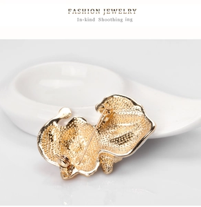 Detail view showing the textured gold metal back and secure pin clasp of the cat brooch