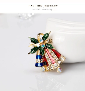 Vue détaillée d'une broche de cloche de Noël festive avec émail coloré et strass scintillants