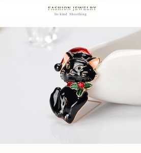 Macro shot of a Christmas black cat brooch with red hat and green gemstone eyes