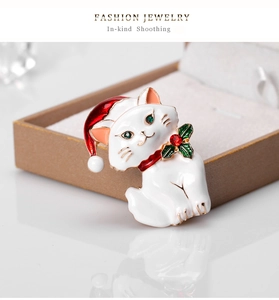 Detail of cute white Christmas cat brooch with red hat on textured jewelry box