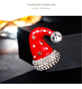 Macro detail of red enamel Christmas hat brooch with glittering silver rhinestones