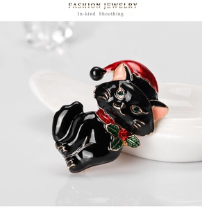 Detail of a Christmas black cat brooch with red hat and green rhinestone eyes on ceramic