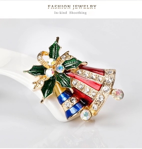 Détail d'une broche de Noël en forme de cloche avec émail coloré et strass brillants