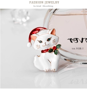 Macro view of Christmas cat brooch with red hat and holly leaves on a clean background