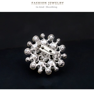 Macro shot of silver sunflower brooch back showing detailed pin clasp and faux pearl edge