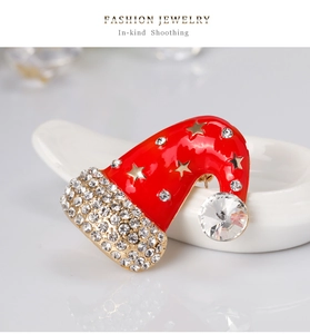 Detail of red enamel Christmas hat brooch with sparkling white rhinestones and gold stars
