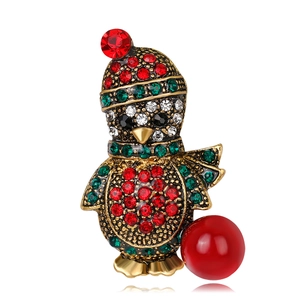 Macro detail of Christmas penguin brooch with sparkling rhinestones and red pearl