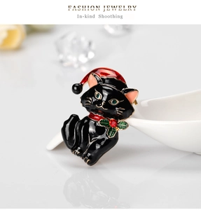 Detail view of a black enamel cat brooch with a red Santa hat and rhinestone accents