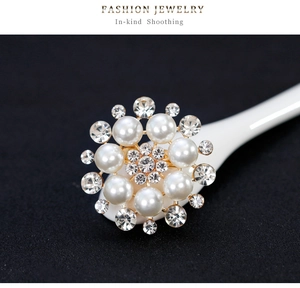 Detail of floral pearl brooch with crystal rhinestones on a golden metal base