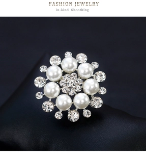 Macro shot of elegant floral pearl brooch with sparkling rhinestones on black leather