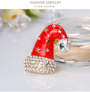 Close-up of a Christmas hat brooch with red enamel, gold stars, and sparkling rhinestones